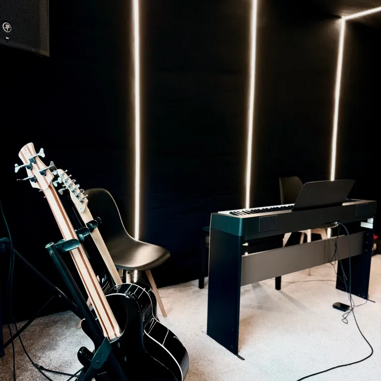 Sala de studio Louder din Baia Mare cu pian digital, chitară și chitară bas, iluminare ambientală